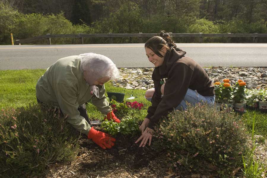A Chi Delta Alpha member (right) works to plant flowers.