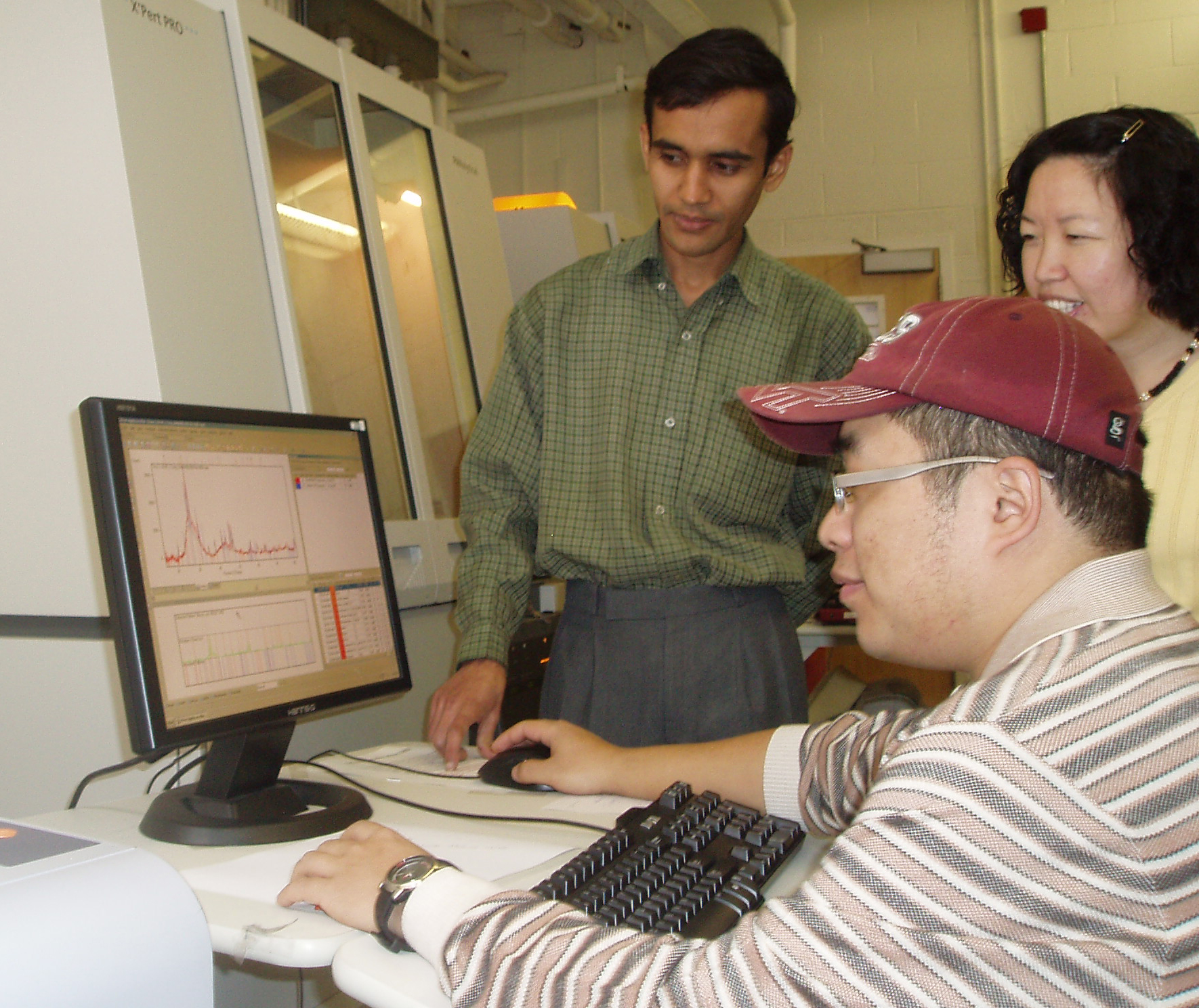 Materials science and engineering doctoral student Manoj Mahapatra, of Egra, Purba Medinipur, India; and Assistant Professor Kathy Lu, standing; and materials science and engineering doctoral student Tongan Jin, of Zhangjiakou, China, seated; are analyzing the seal glass to see the resistance to devitrification (crystalline growth) of the material.