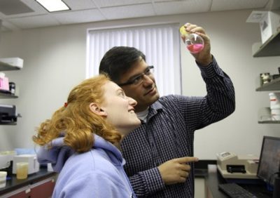 Graduate student Michelle Oppenheimer and Pablo Sobrado examine the contents of a beaker in a Fralin Hall laboratory.