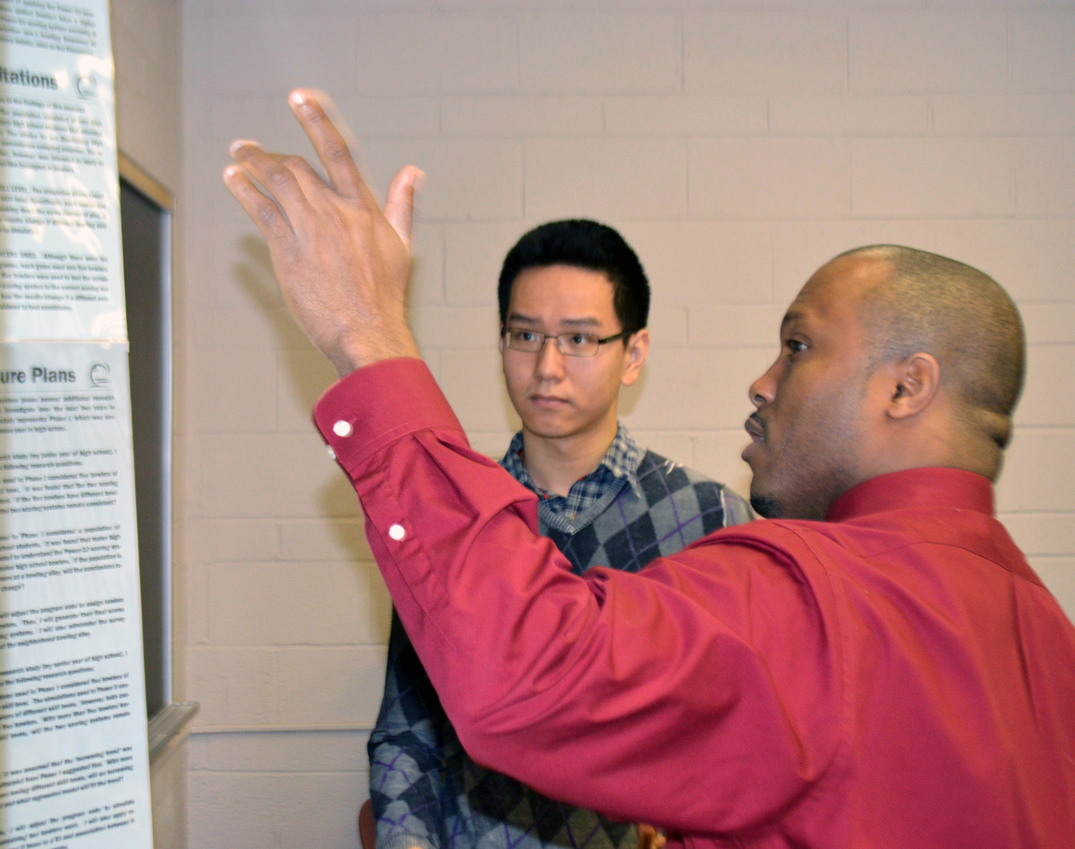 Marlow Lemons reviews a poster presentation with high school sophomore Bright Zheng