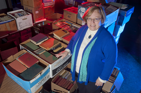 Leisa Osborne stands in a room with many boxes of books