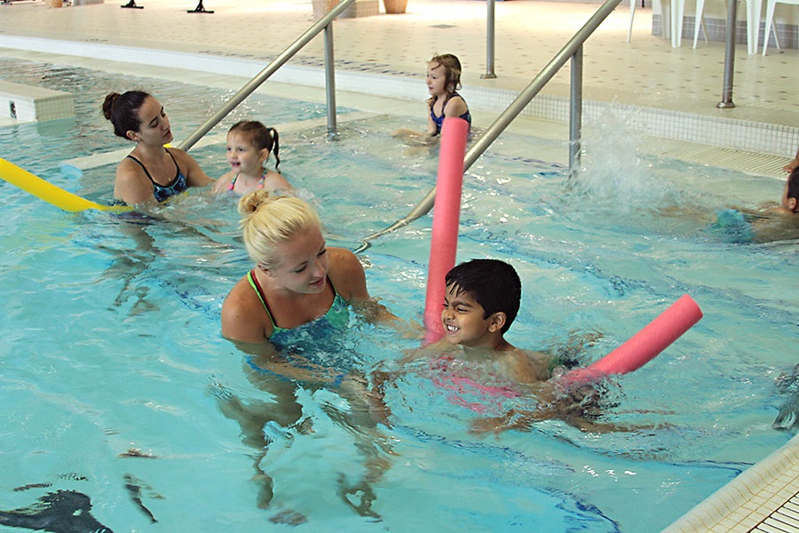 Swim instructors helping young people learn to swim