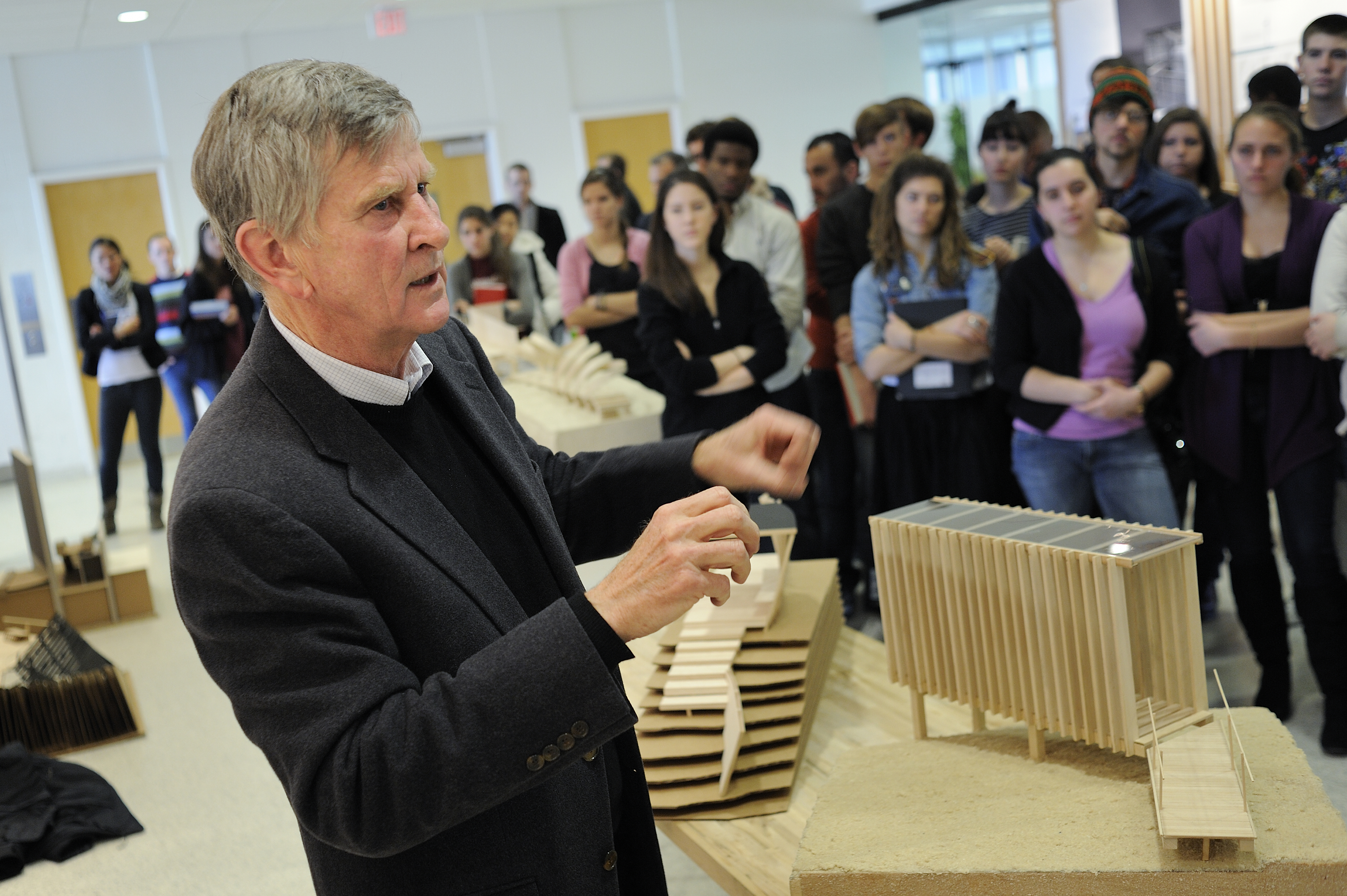 Robert Dunay discusses architectural models with students in the lobby of Cowgill Hall. 