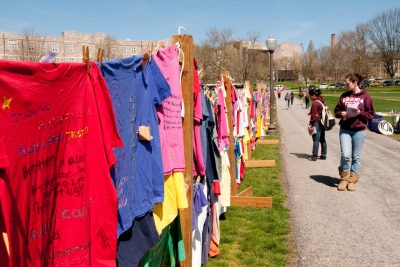 Individuals who have been impacted by violence against women, either themselves or a friend or family member, create shirts to go on display as part of the Clothesline Project. The different colors represent different types of violence.