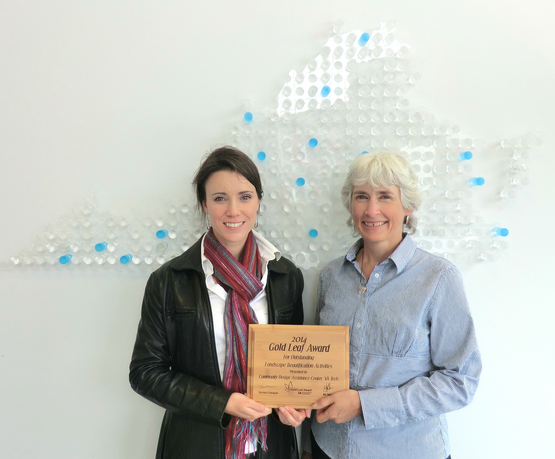 Lara Browning and Elizabeth Gilboy hold the wooden plaque they received for the Gold Leaf Award.