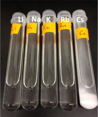 A row of five test tubes containing solutions