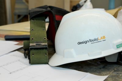 A helmet and toolbelt sit on top of building plans. 