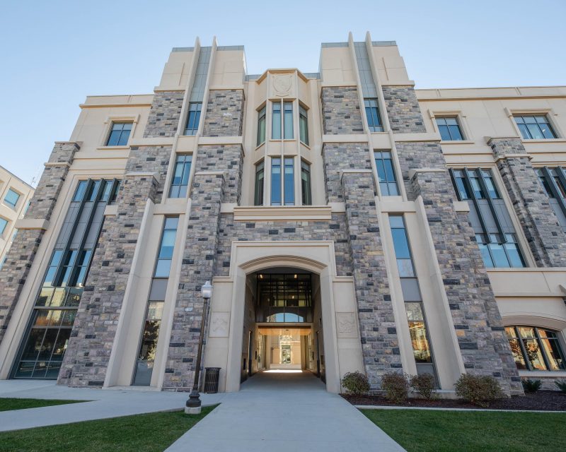 Exterior of Holden Hall features three stories of Hokie Stone and windows. On the lower level there is a walkway with an arch that enters the building. 